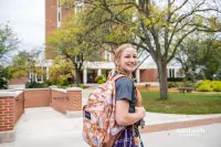 student walking in front of the library