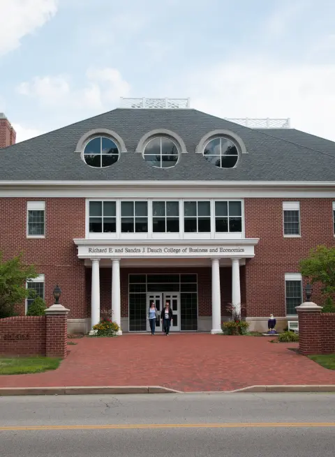 Two individuals walking out of the front of the Dauch College of Business and Economics.