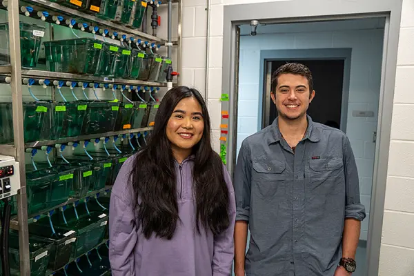Leap Vathanak and Luke Bowen pose next to zebrafish