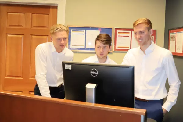 three business capstone students in front of computer