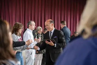 AU President Carlos Campo lights candles of attendees at Holocaust Remembrance Day.