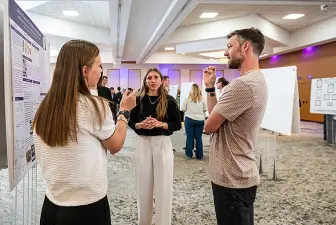 Professor Chris Chartier speaking with students at the 2026 URCA Symposium
