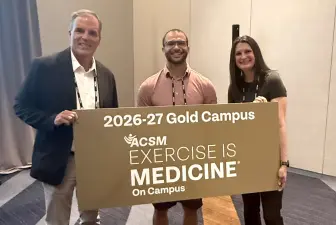 Levi Jones poses with an Exercise is Medicine gold campus sign at the 2026 American College of Sports Medicine annual meeting.