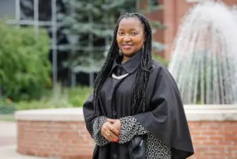 Rosaire Ifedi in graduation gown in front of fountain