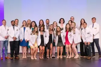 AU’s physician assistant students on stage in their white coats