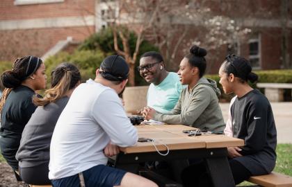 Undergraduate students sitting around a picnic table on the Quad