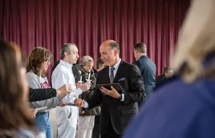 AU President Carlos Campo lights candles of attendees at Holocaust Remembrance Day.