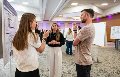 Professor Chris Chartier speaking with students at the 2026 URCA Symposium