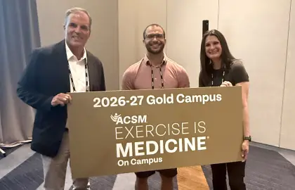Levi Jones poses with an Exercise is Medicine gold campus sign at the 2026 American College of Sports Medicine annual meeting.