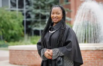 Rosaire Ifedi in graduation gown in front of fountain