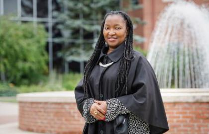Rosaire Ifedi in graduation gown in front of fountain
