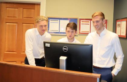 three business capstone students in front of computer
