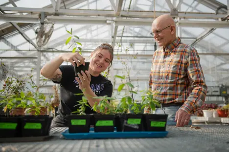 student and faculty member in greenhouse