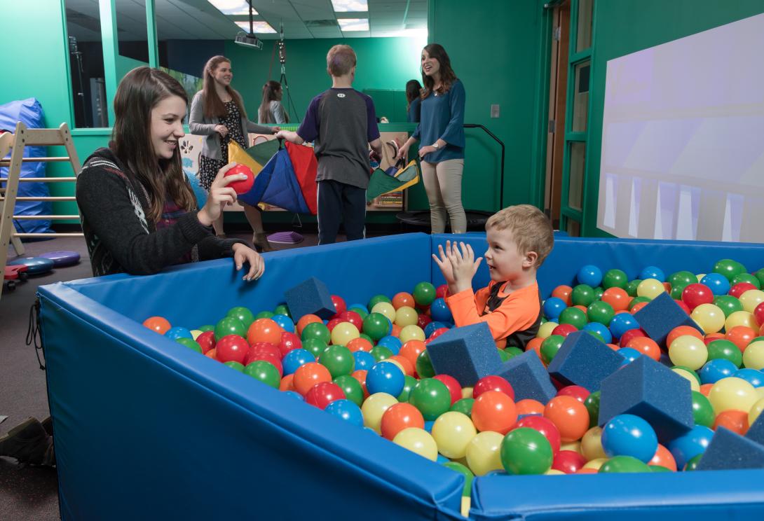 College of Education student works with elementary student in the sensory room ball pit