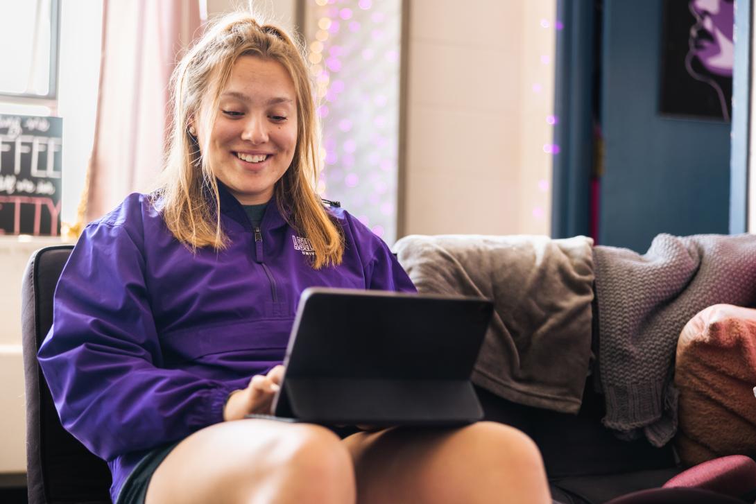 Student using a laptop while sitting on a couch