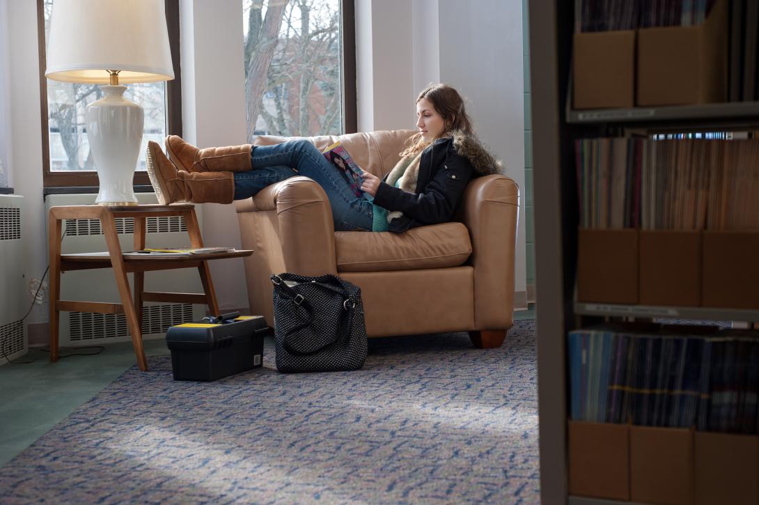 Student laying on a couch in the library studying