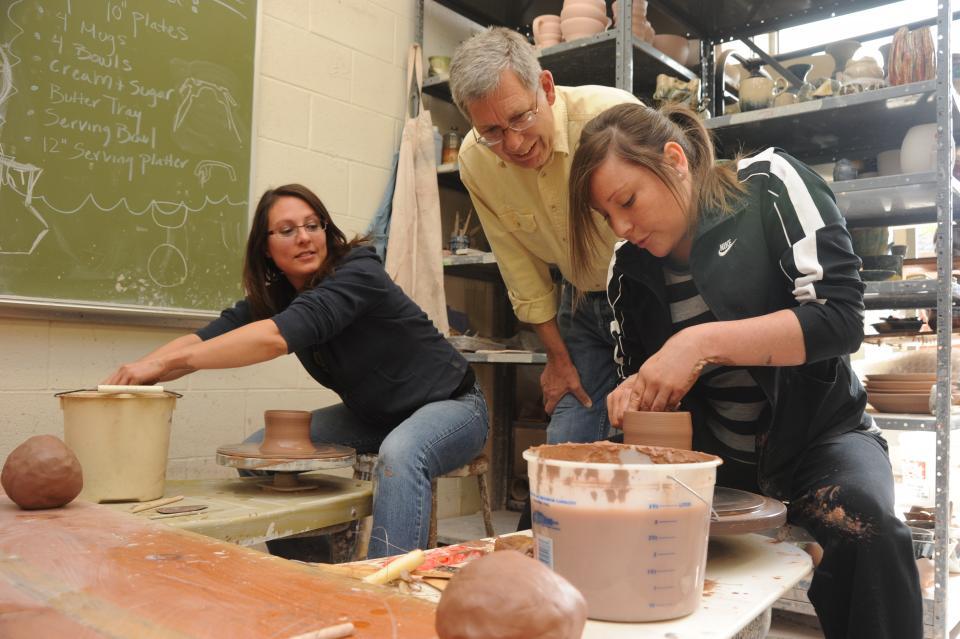 Ceramics students throwing clay on pottery wheel