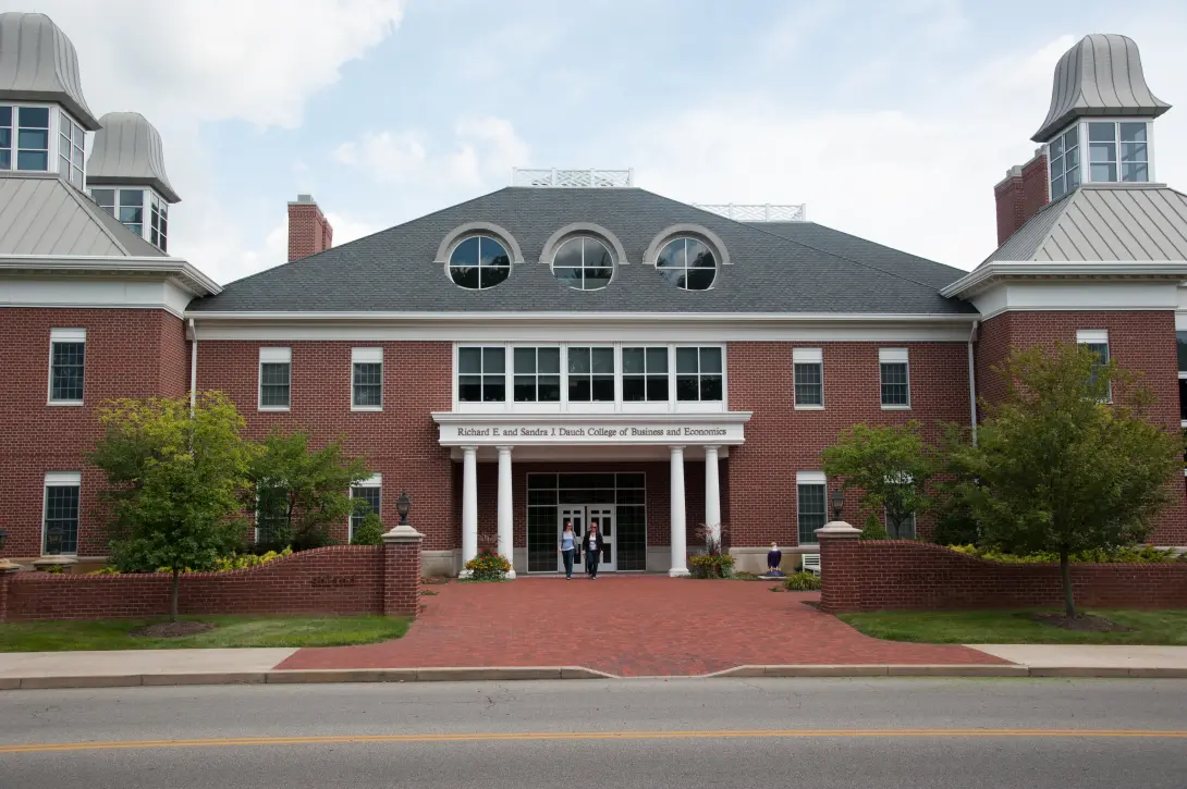 Two individuals walking out of the front of the Dauch College of Business and Economics.