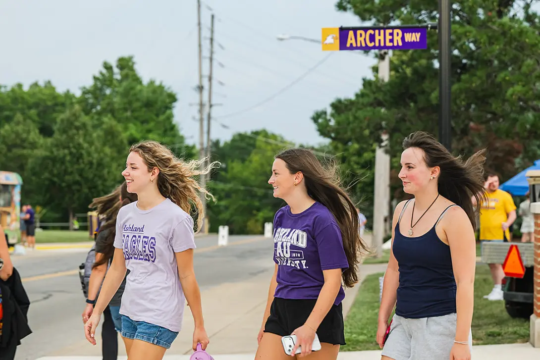 Three students walking with new Archer Way street sign in background