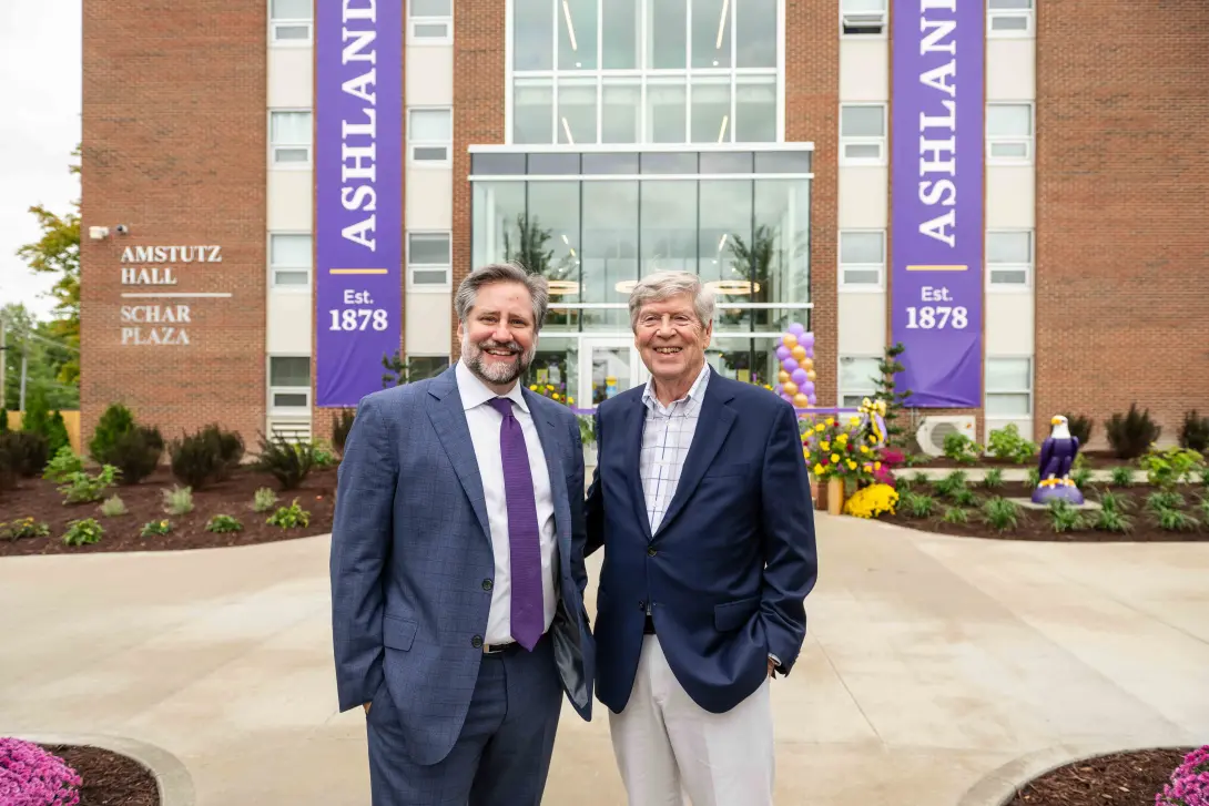 President Jon Parrish Peede and Dwight Schar pose for a photo outside the main entrance of Amstutz Hall